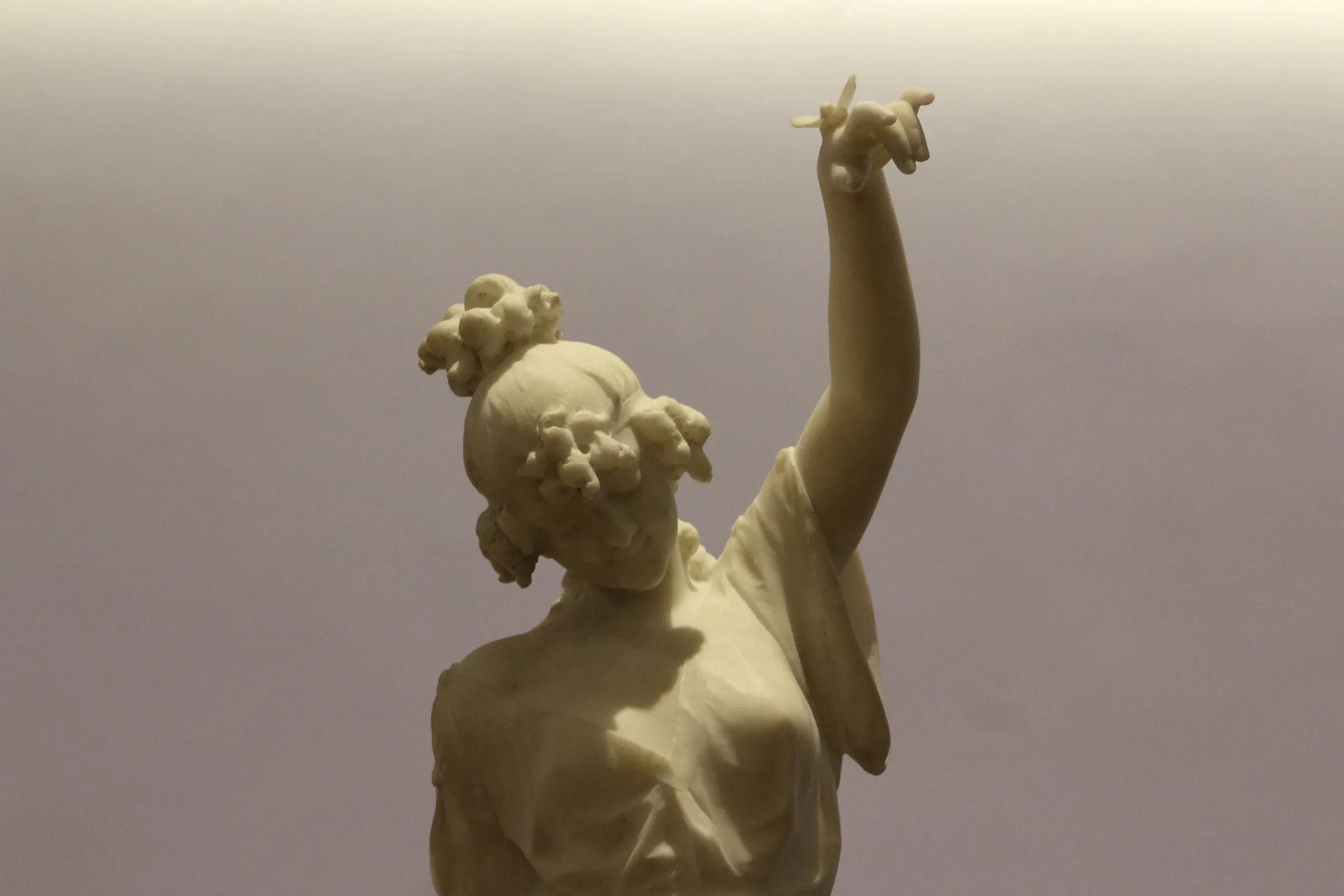 Figura en mármol con flores en el cabello y un brazo alzado