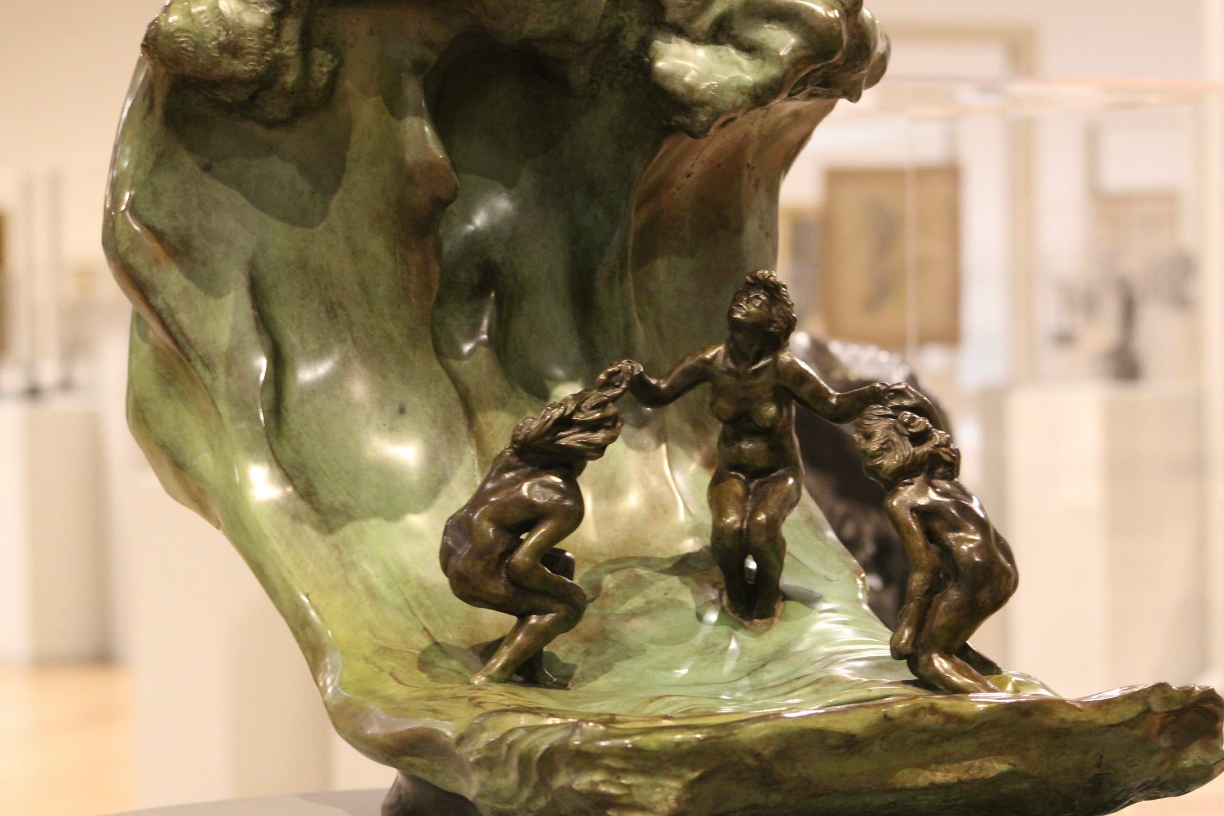 Escultura de una ola en bronce y piedra verde con figuras