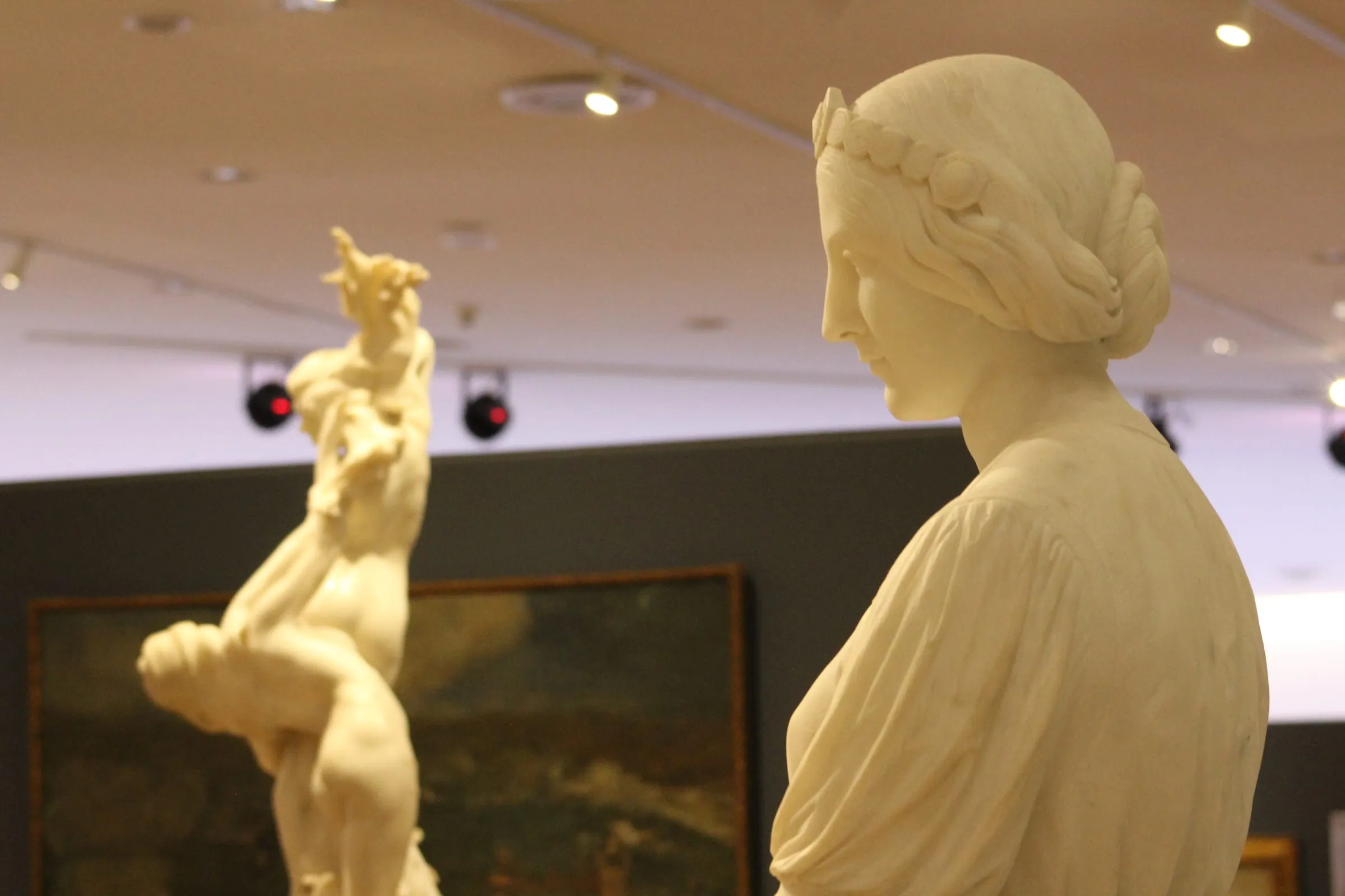 Busto de mármol en una sala de museo con otras obras al fondo