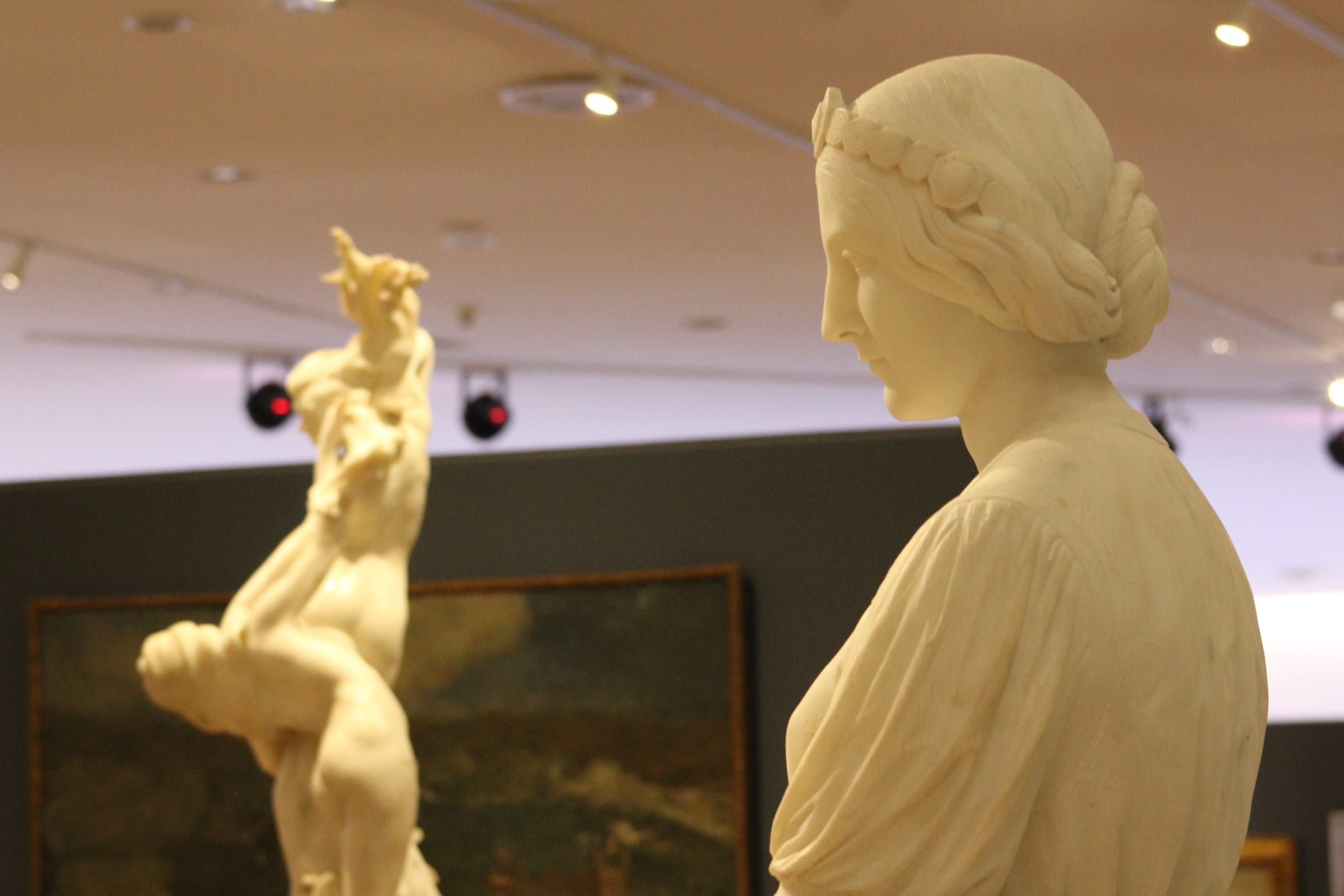 Busto de mármol en una sala de museo con otras obras al fondo